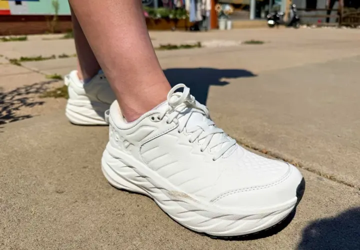 White walking shoes on a sidewalk. The question of whether walking shoes should be a size bigger is on many minds.