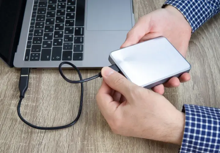 Hände verbinden eine externe Festplatte mit einem Laptop. Plötzlich kein Zugriff auf externe Festplatte.