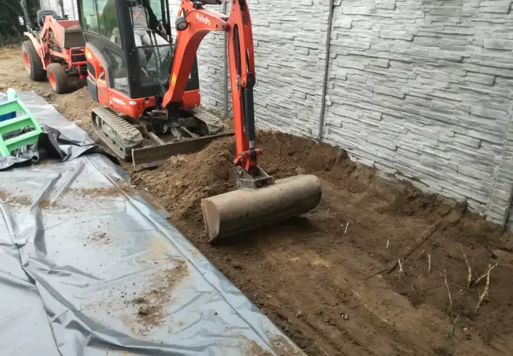 Koparka pracuje nad przygotowaniem terenu pod budowę, usuwając ziemię i przygotowując podłoże.