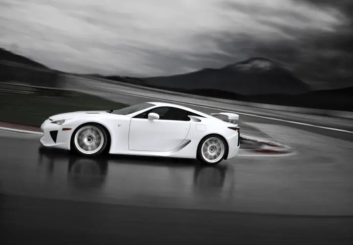 Biały Lexus LFA na torze wyścigowym, z rozmytym tłem gór i nieba.