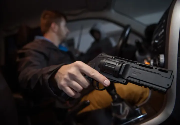 Mężczyzna w samochodzie trzyma pistolet na kule gumowe. Czy pistolet na kule gumowe jest legalny? To pytanie nurtuje wielu.