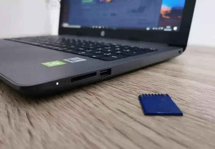 Obok laptopa leży niebieska karta pamięci. Dysk jest zabezpieczony przed zapisem, co uniemożliwia modyfikację danych.