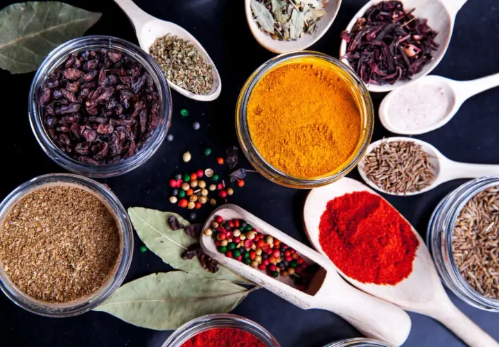 Kolorowe przyprawy, w tym kurkuma, papryka i kmin rzymski, ułożone na czarnym tle. Idealne do przygotowania aromatycznego garam masala przepis.
