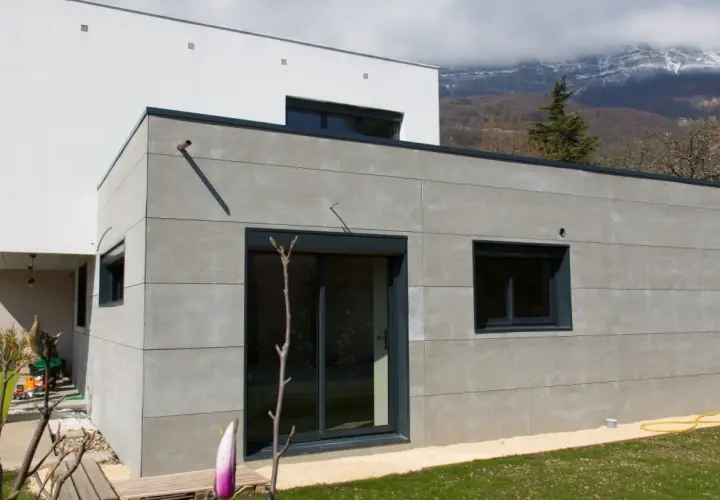 Extension moderne en parpaing gris, 20m2, avec grandes baies vitrées et vue sur montagnes. Estimation du prix extension 20m2 en parpaing.