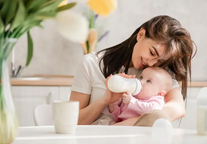 Mama karmi niemowlaka z butelki. Uważaj na przekarmienie niemowlaka mlekiem modyfikowanym objawy, by uniknąć problemów.