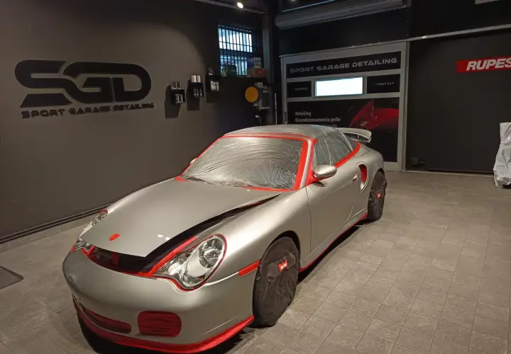 Auto sportiva argentata, mascherata per la preparazione. Inizia il processo per come lucidare auto in questo centro di detailing.