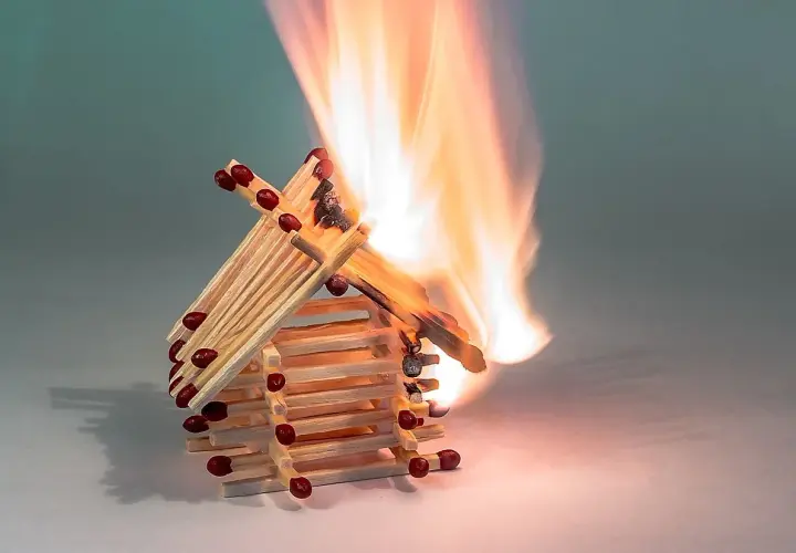 Ein Haus aus Streichhölzern brennt lichterloh. Die Flammen zeigen, ab wann Holz brennt.