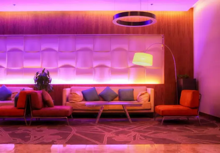 Nowoczesny hotel butikowy co to? Wnętrze z sofami, fotelami i designerską lampą w fioletowym świetle.