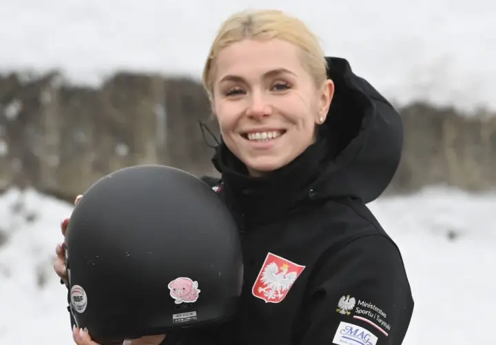 Uśmiechnięta Klaudia Adamek trzyma kask. Na jej kurtce widnieje godło Polski.