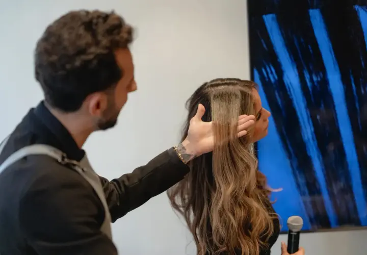 Hombre revisa el pelo elastico de una mujer, mostrando su textura y brillo.