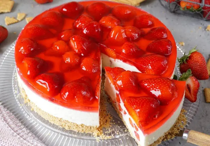Ein köstlicher Erdbeerkuchen ohne Backen, mit frischen Erdbeeren und rotem Tortenguss auf cremigem Boden.