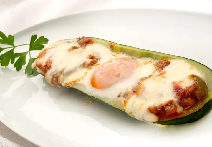 Deliciosos calabacines rellenos con huevo y queso gratinado, adornados con perejil fresco.
