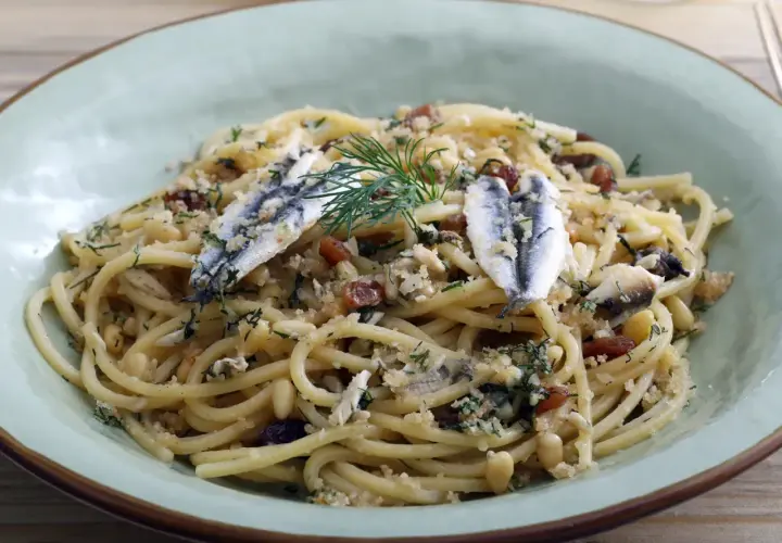 Un plat de pâtes aux sardines, garni de pignons de pin, de raisins secs et d'aneth frais.