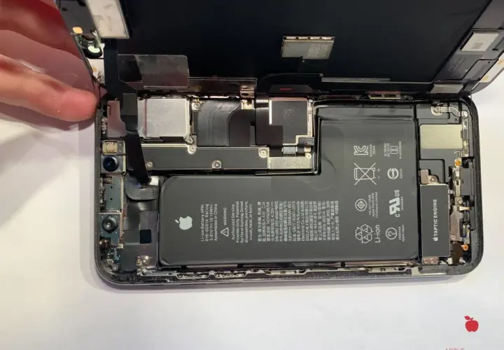 Rozłożony iPhone, gotowy do usuwania wody. Widać baterię, aparat i inne komponenty.
