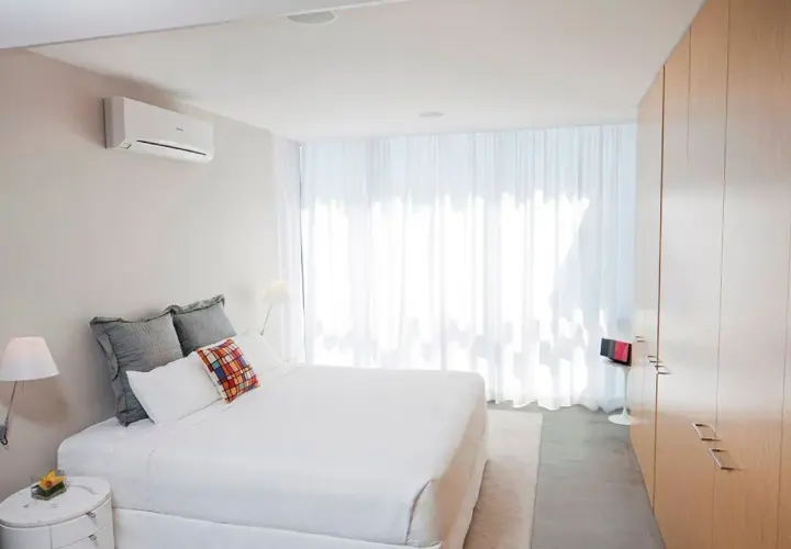 Un dormitorio moderno con aire acondicionado en la pared, ideal para saber donde colocar el aire acondicionado en un dormitorio.