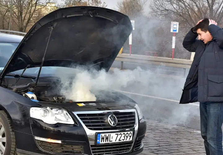 Zmartwiony kierowca przy dymiącym silniku. Zastanawia się, ile kosztuje wyjęcie silnika z samochodu po awarii.