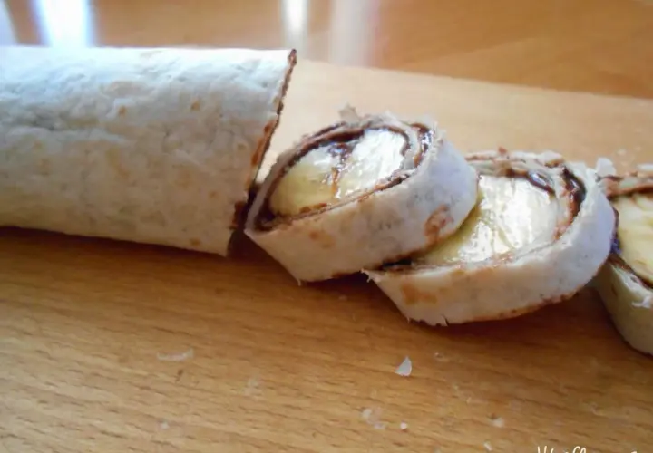 Roladki z tortilli z bananem i czekoladą na desce.