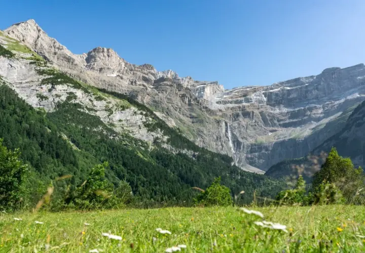 Majestuoso circo de Gavarnie con cascada y prado verde.