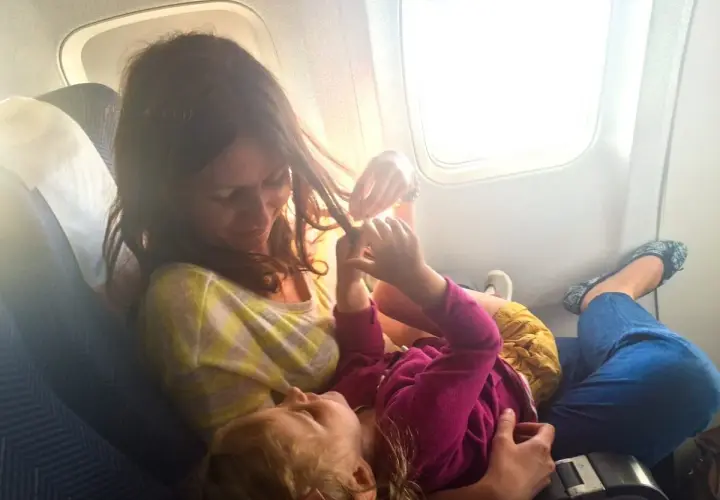 Mama bawi się włosami dziecka, szukając pomysłów, czym zająć dziecko w samolocie.