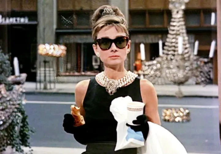 Holly Golightly, icona di stile, gusta un croissant davanti a Tiffany. Le sue recensioni su "Colazione da Tiffany" sarebbero sicuramente positive!