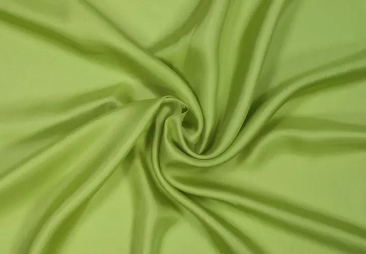 Drapé de tissu sergé vert pomme, doux et soyeux, formant des plis élégants.