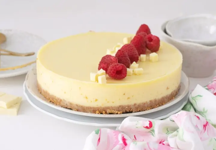 Deliciosa tarta de chocolate blanco, decorada con frambuesas frescas y trocitos de chocolate. ¡Un postre irresistible!