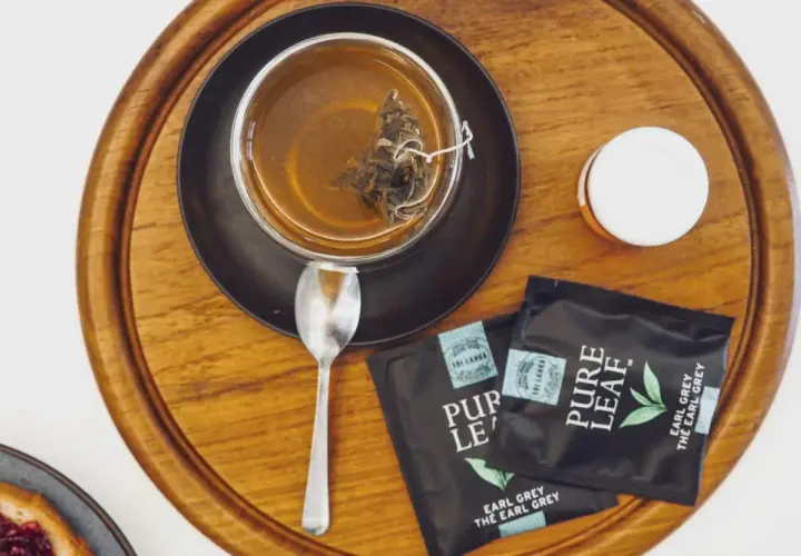 Aromatyczna, najlepsza czarna herbata Earl Grey z Sri Lanki, zaparzona w szklance, obok saszetki i łyżeczka.