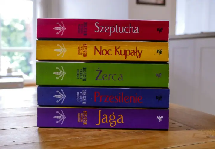 Pięć kolorowych książek Katarzyny Bereniki Miszczuk ułożonych jedna na drugiej. Na okładkach widnieje symbol kwiatu paproci.