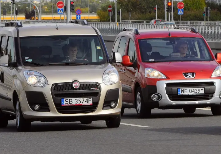 Złoty Fiat i czerwony Peugeot jadące po drodze.