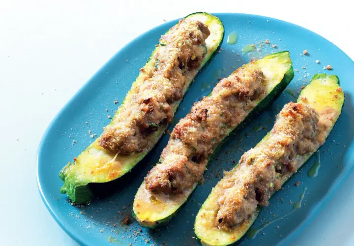 Tre zucchine ripiene velocissime, dorate e appetitose, servite su un piatto blu.