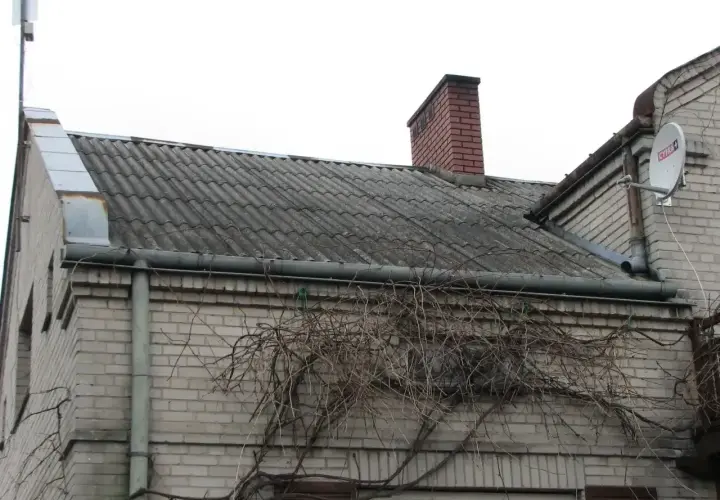 Dach pokryty eternitem, który zawiera azbest. Co to za materiał? Widać też komin i antenę satelitarną.