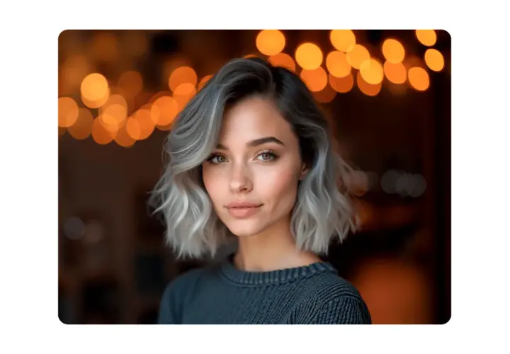 Mujer con pelo corto rubio platino ceniza, mirada cautivadora y luces de bokeh cálidas de fondo.