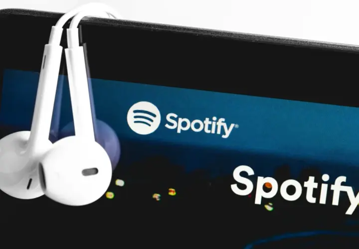Słuchawki wiszące na ekranie smartfona z logo Spotify.