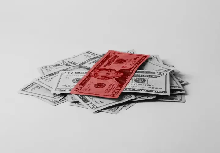 Stos dwudziestodolarowych banknotów, z jednym czerwonym na wierzchu, symbolizuje fundusz gwarantowanych świadczeń pracowniczych.
