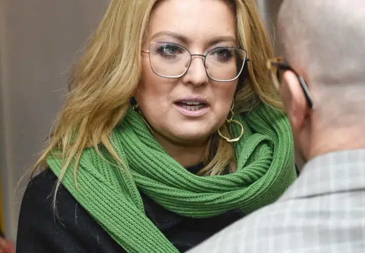 Kinga Burzyńska w zielonym szaliku i okularach rozmawia z mężczyzną.
