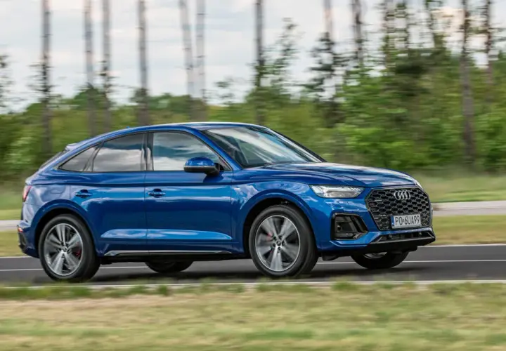 Błękitny Audi Q5 Sportback 2025 w ruchu, z rozmytym tłem lasu. Dynamiczna sylwetka i sportowy charakter.