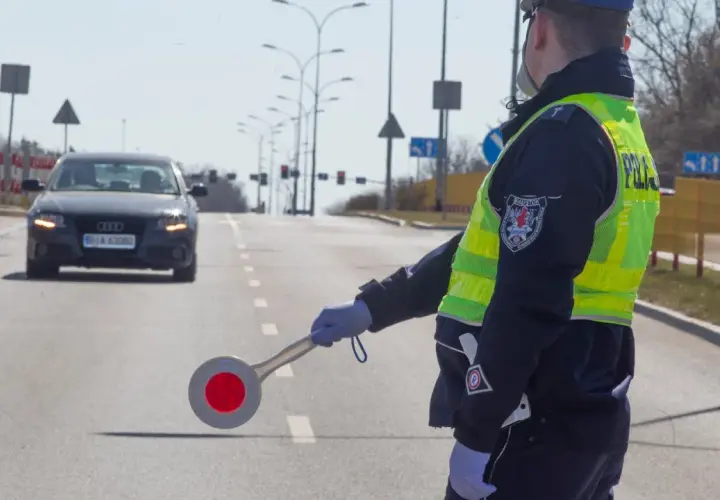 Policjant w kamizelce odblaskowej kieruje ruchem, zatrzymując audi. Nie ma tu fotoradaru, ale kontrola drogowa trwa.