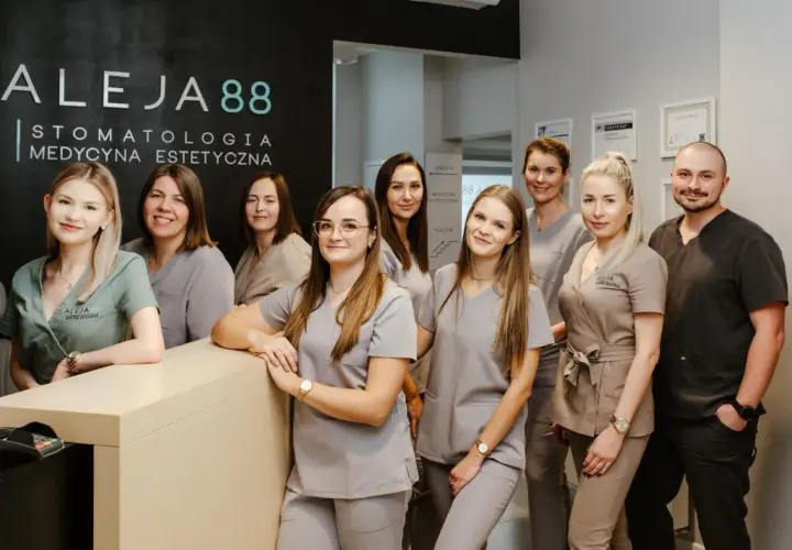 Zespół uśmiechniętych dentystów i personelu medycznego w gabinecie stomatologicznym.