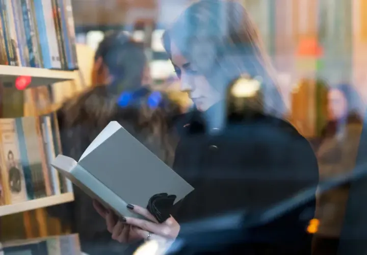 Kobieta czyta książkę w księgarni. Autorzy mogą poznać jakie dane o sprzedaży książek są dostępne dla nich dzięki Nielsen Bookscan.