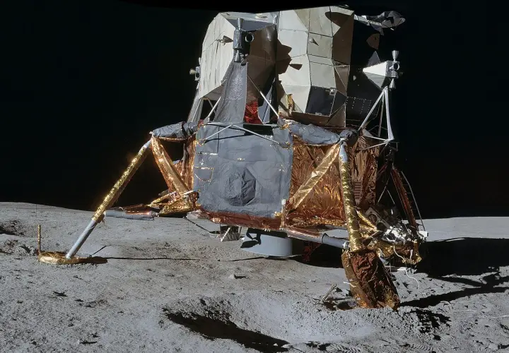 Moduł księżycowy z misji **projekt Apollo** osadzony na szarym gruncie Księżyca.