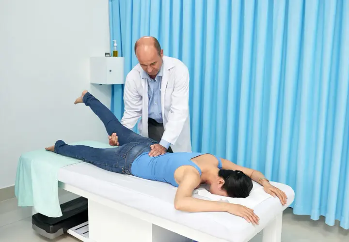 Fizjoterapeuta wykonuje test Mennella na pacjentce leżącej na kozetce.