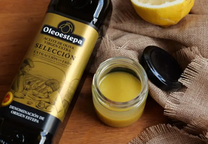 Ingredientes para una vinagreta de mostaza: botella de aceite de oliva virgen extra, un tarro con la vinagreta y un limón.