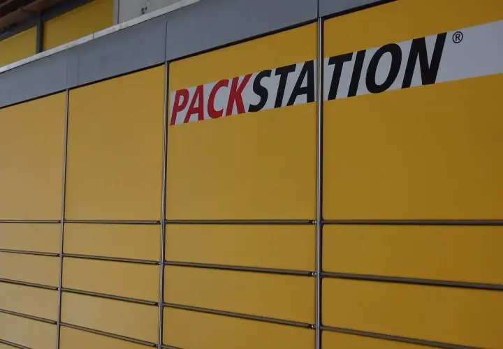 Żółta ściana z rzędami skrytek i napisem "PACKSTATION". To sieć punktów odbioru paczek, popularna także w Niemczech.