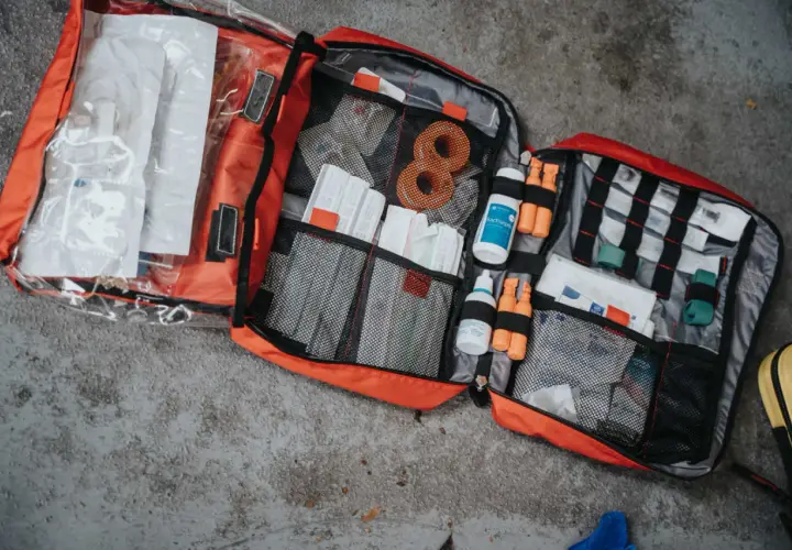 Rozłożona apteczka turystyczna w góry, pełna plastrów, bandaży, płynów dezynfekujących i innych niezbędnych akcesoriów.