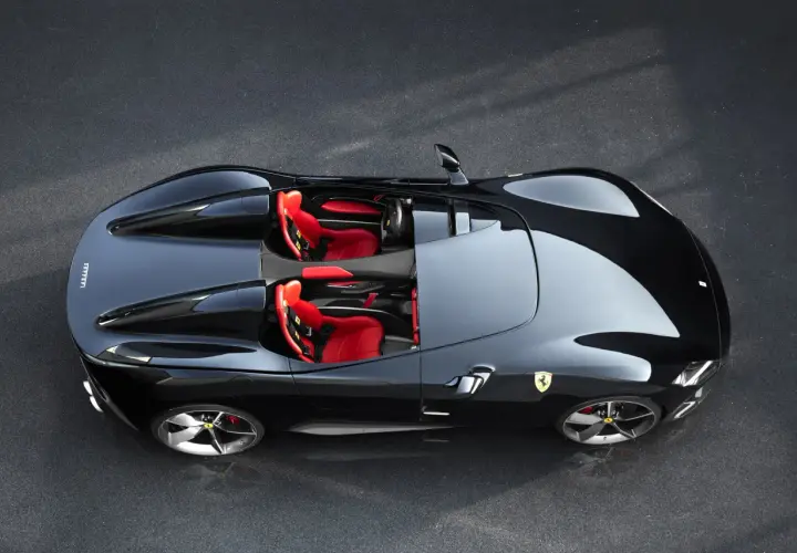 Czarny Ferrari Monza SP2 z czerwonymi siedzeniami, gotowy do jazdy po torze.
