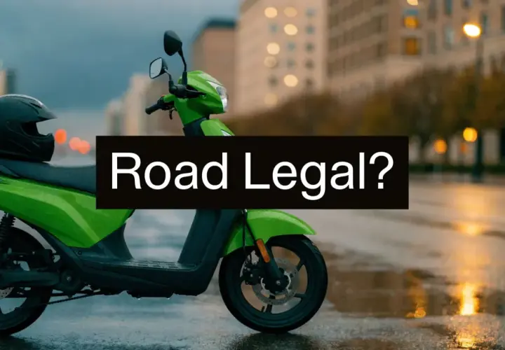 Zielony motorower z kaskiem na siedzeniu, stojący na mokrej ulicy. Czy to motorower co to, legalny na drogach?