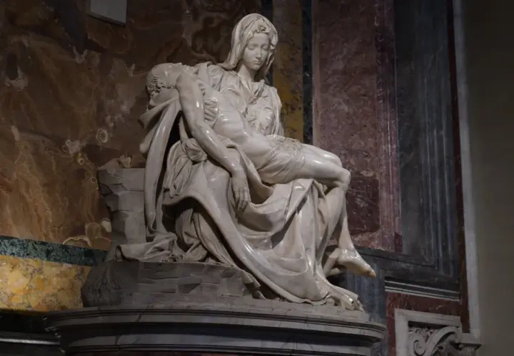 Pieta Michała Anioła: Matka Boska tuli martwe ciało Jezusa. Marmurowa rzeźba pełna bólu i piękna.