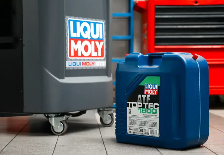 Niebieski kanister z olejem Liqui Moly ATF Top Tec 1800 w warsztacie. Zastanawiasz się, ile bierze mechanik za wymianę oleju?