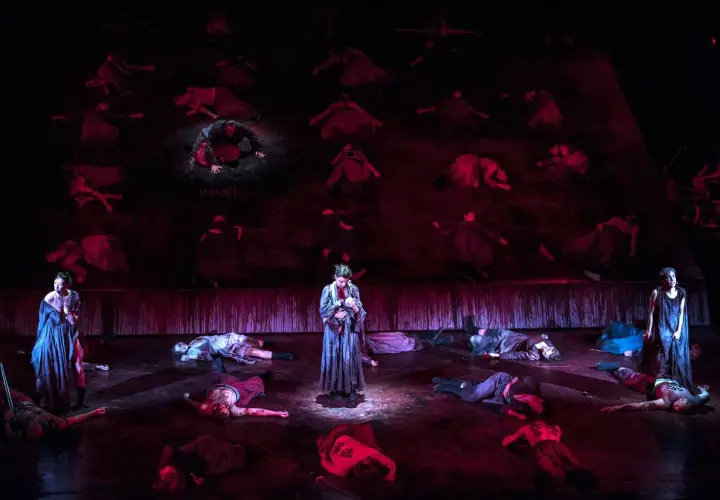 Scena z "Makbeta" w Teatrze Muzycznym Wrocław. Na scenie leżą martwi, stoi postać z dzieckiem.