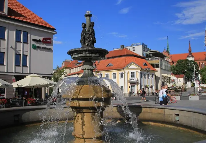 Fontanna na Rynku Kościuszki w Białymstoku, otoczona kawiarniami i zabytkową architekturą.
